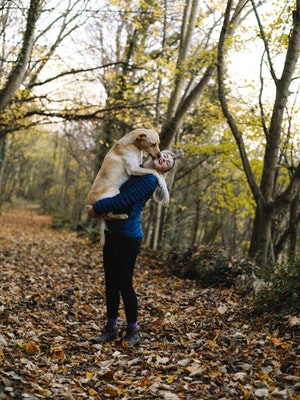 Dog on owner licking face in the woods